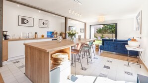 A modern kitchen with a wooden island, a dining area with chairs, and a blue sofa in a living room. - House with swimming pool 10 minutes walk from the beach  (Toulon)