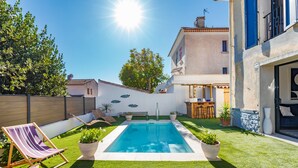 A swimming pool with a small deck area, surrounded by a well-maintained lawn and potted plants. - House with swimming pool 10 minutes walk from the beach  (Toulon)