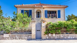 A two-story house with a tiled roof, a stone wall, and a metal gate. - House with swimming pool 10 minutes walk from the beach  (Toulon)