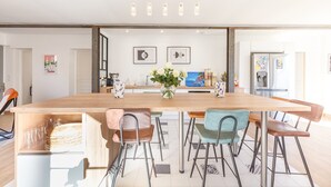 A modern kitchen with a long wooden table, six chairs, a vase with flowers, and a refrigerator. - House with swimming pool 10 minutes walk from the beach  (Toulon)