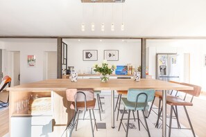 Eine moderne Küche mit einer Holzinsel, Barhocker und einem Blumenstrauß.