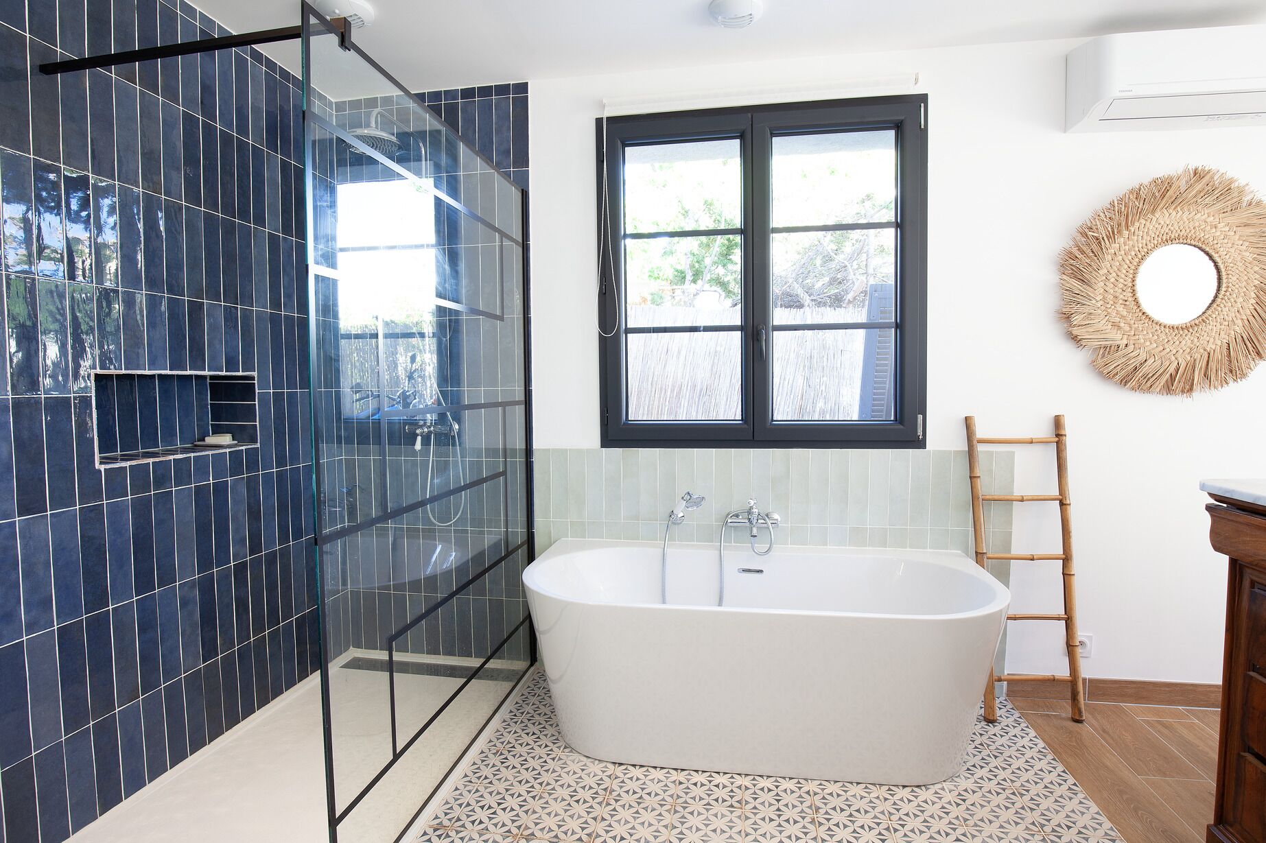 Ein modernes Badezimmer mit freistehender Badewanne, einer gläsernen Duschkabine und einem Fenster für natürliches Licht.