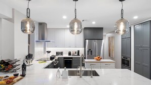Una cucina moderna con un piano di lavoro in marmo, elettrodomestici in acciaio inossidabile e illuminazione a sospensione.
