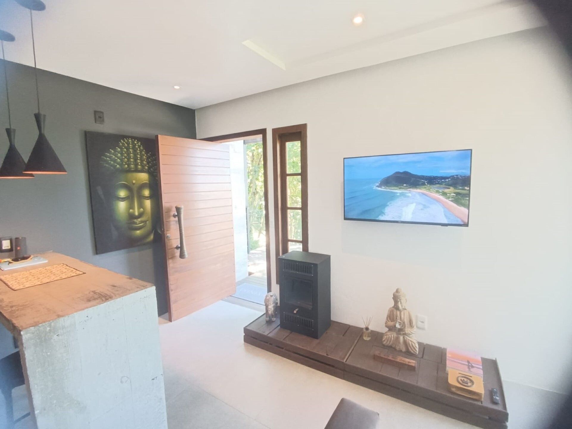 En modern inredning med en Buddha-staty, en tv och en liten statyett på en hylla.
