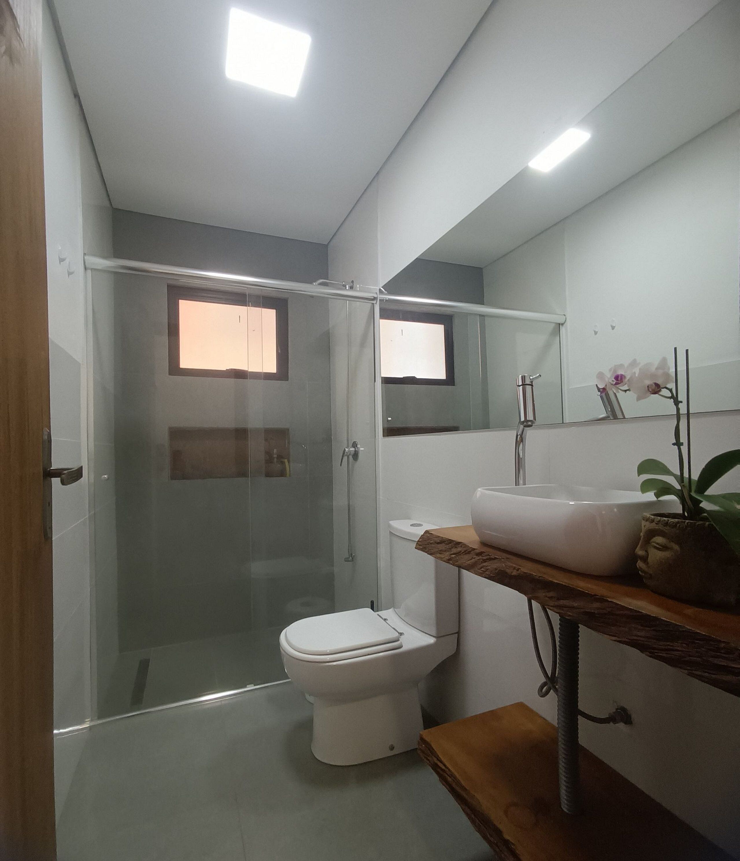 A modern bathroom with a glass shower enclosure, a white toilet, and a vanity with a sink and mirror.