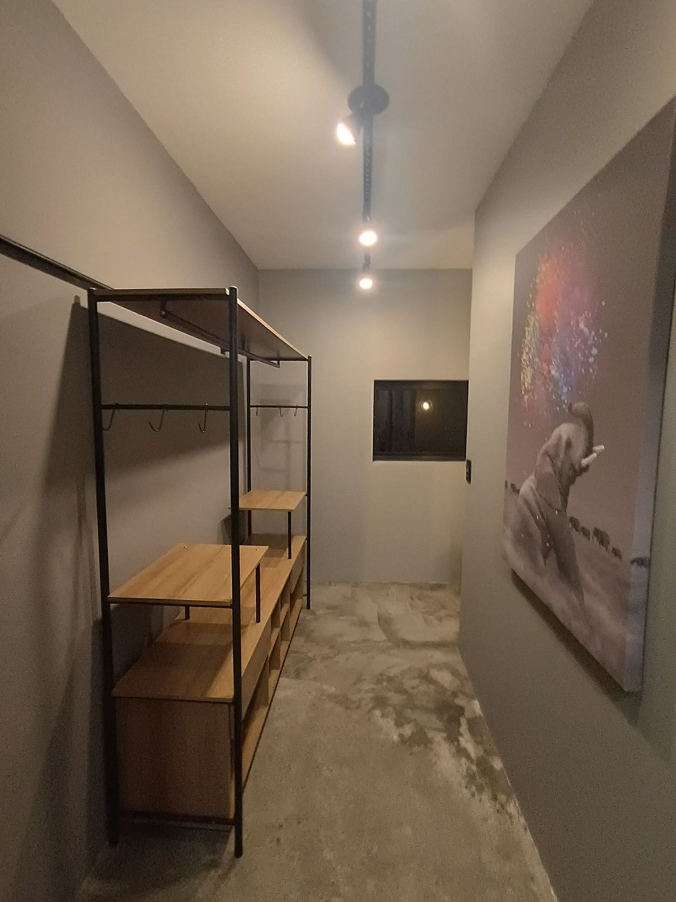 A room with a bunk bed, a small window, and a painting on the wall.