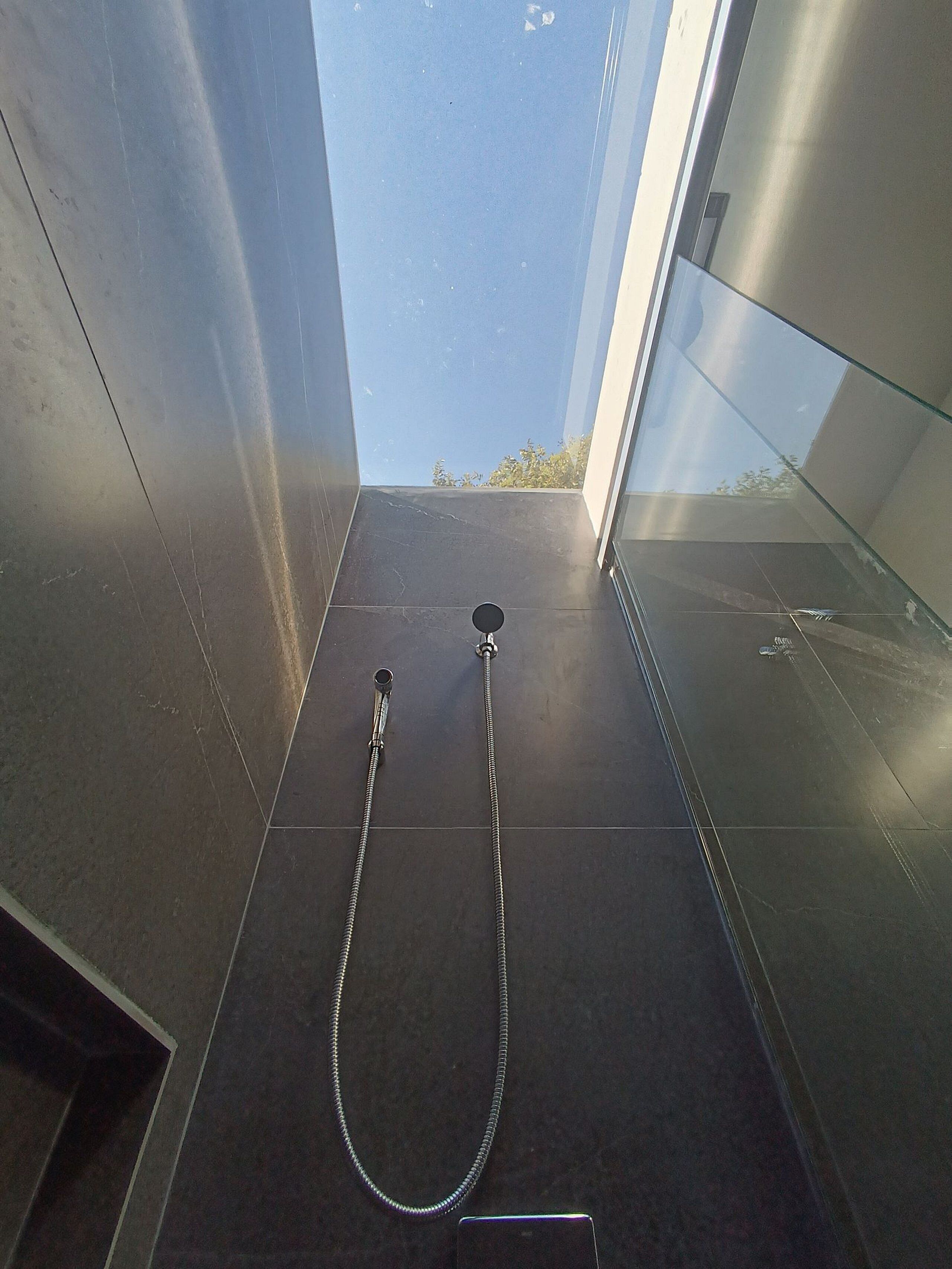 Ein modernes Badezimmer mit Duschkabine aus Glas, einer Handbrause und einem sichtbaren Handtuchhalter.