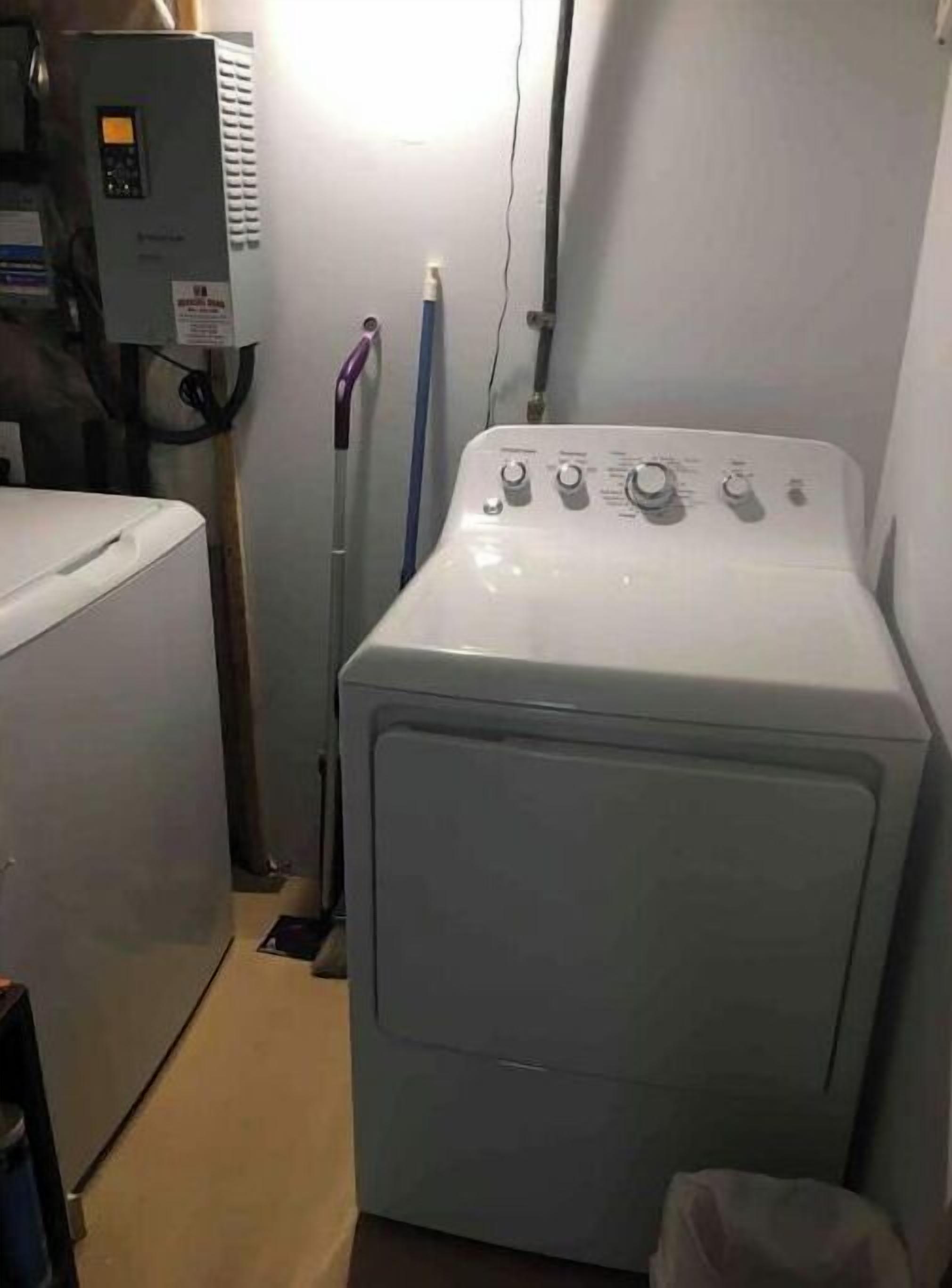 Une buanderie équipée d’un lave-linge à chargement frontal, d’un sèche-linge et d’un mur utilitaire avec un panneau de commande.