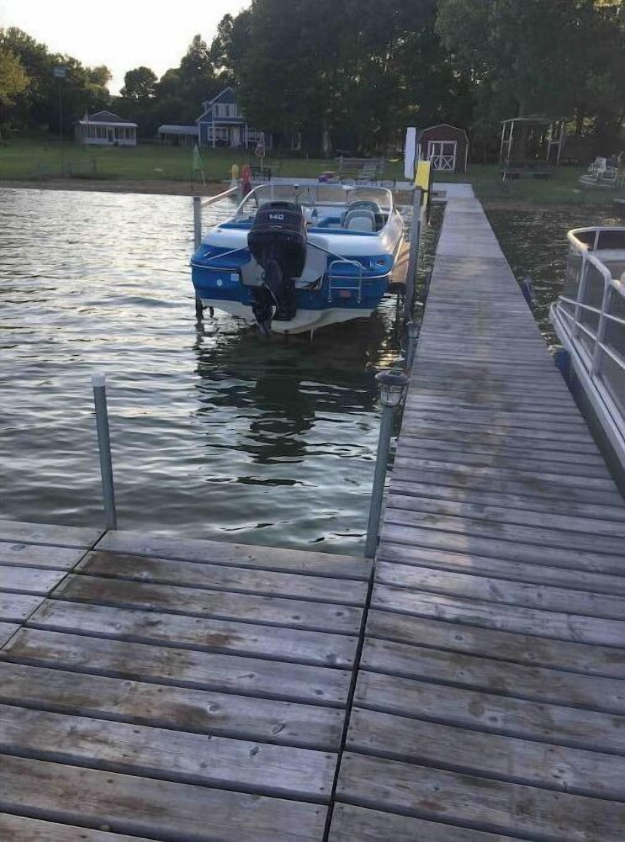 Une jetée en bois s’étendant sur une étendue d’eau calme, avec un bateau amarré à son extrémité.