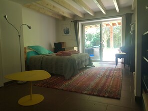 Une chambre avec un lit, un bureau, une chaise, une télévision et un balcon.