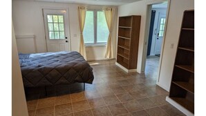 Une chambre à coucher avec un lit, une fenêtre avec des rideaux, une porte et une bibliothèque intégrée.