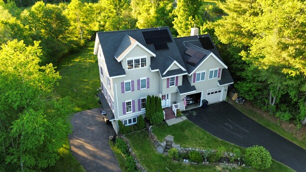 Une grande maison à deux étages avec un garage, entourée d’une végétation luxuriante.