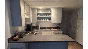 Une cuisine de taille réduite avec des meubles blancs, un four à micro-ondes, une cuisinière et un évier.