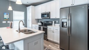 A modern kitchen with white cabinets, stainless steel appliances, and a built-in island with a sink.