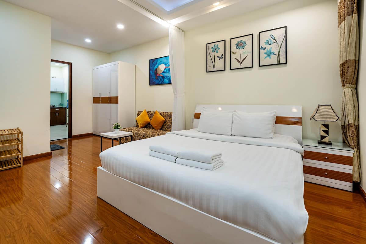 Une chambre d’hôtel avec un grand lit, une armoire, une petite table et une chaise.