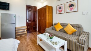 A modern living room with a sofa, a coffee table, a TV, and a wardrobe. - WE HOME Japan Town (Ho Chi Minh City)