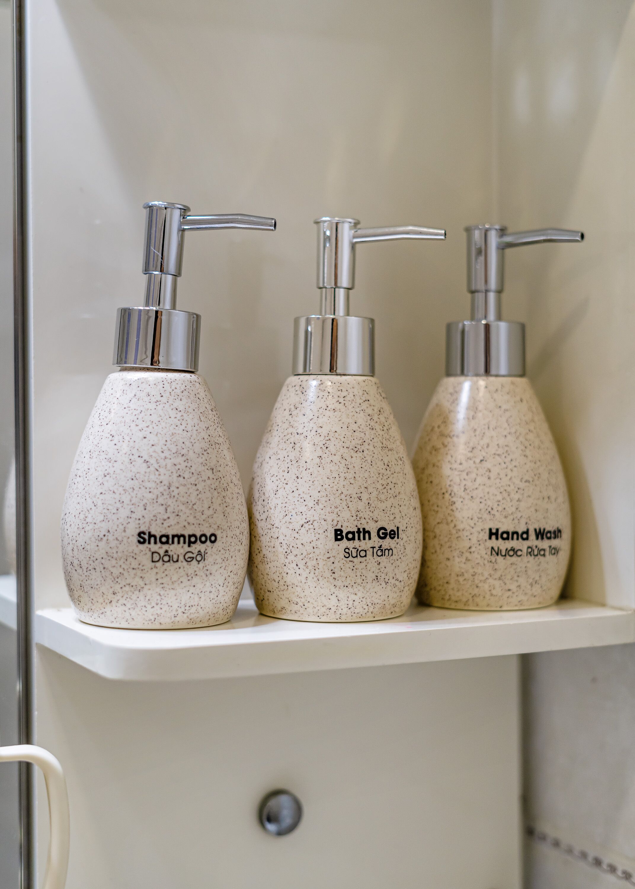 Three toiletry bottles on a bathroom shelf.