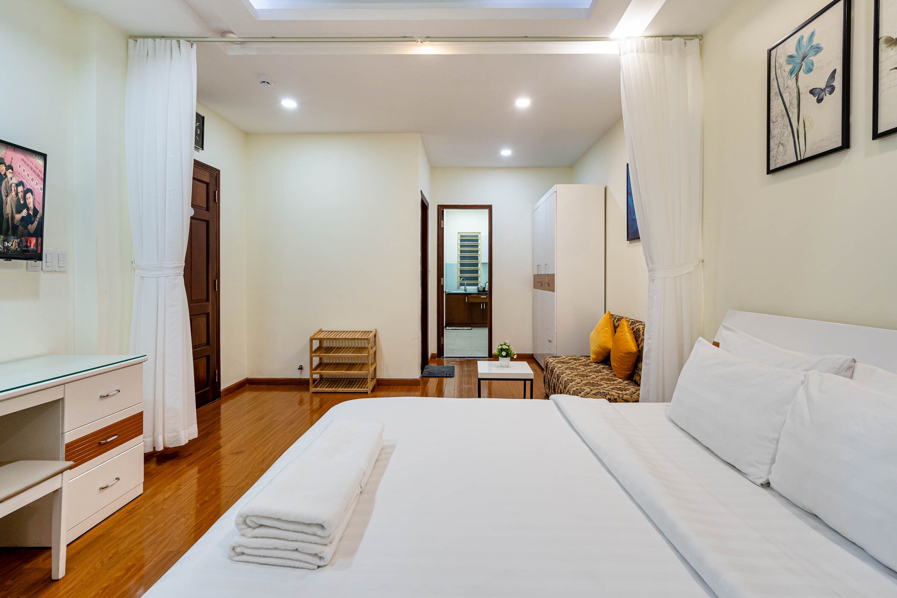 Une chambre d’hôtel comprenant un lit, un bureau, une chaise, une petite table et une armoire.