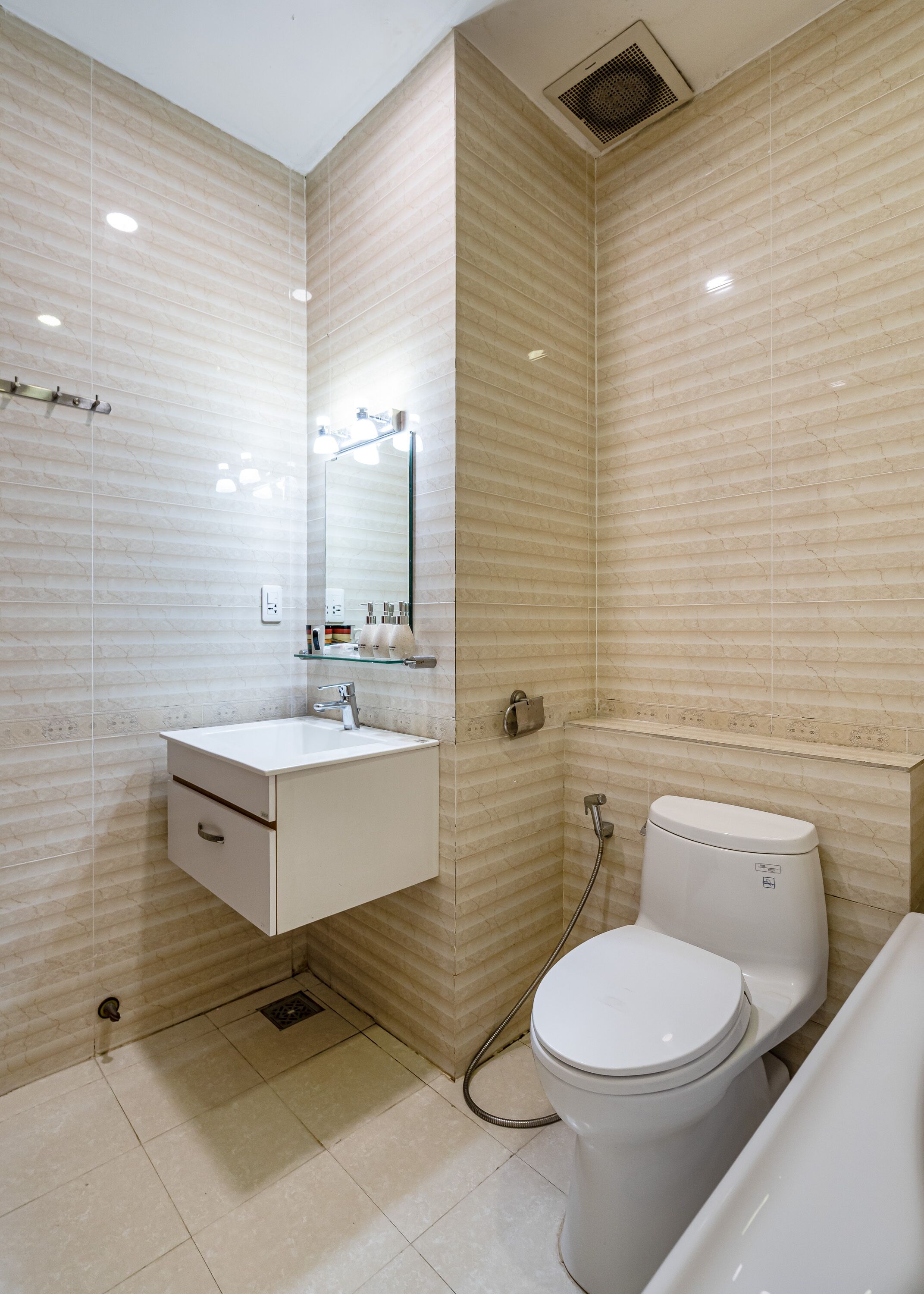 A modern bathroom with a white sink, mirror, and toilet.