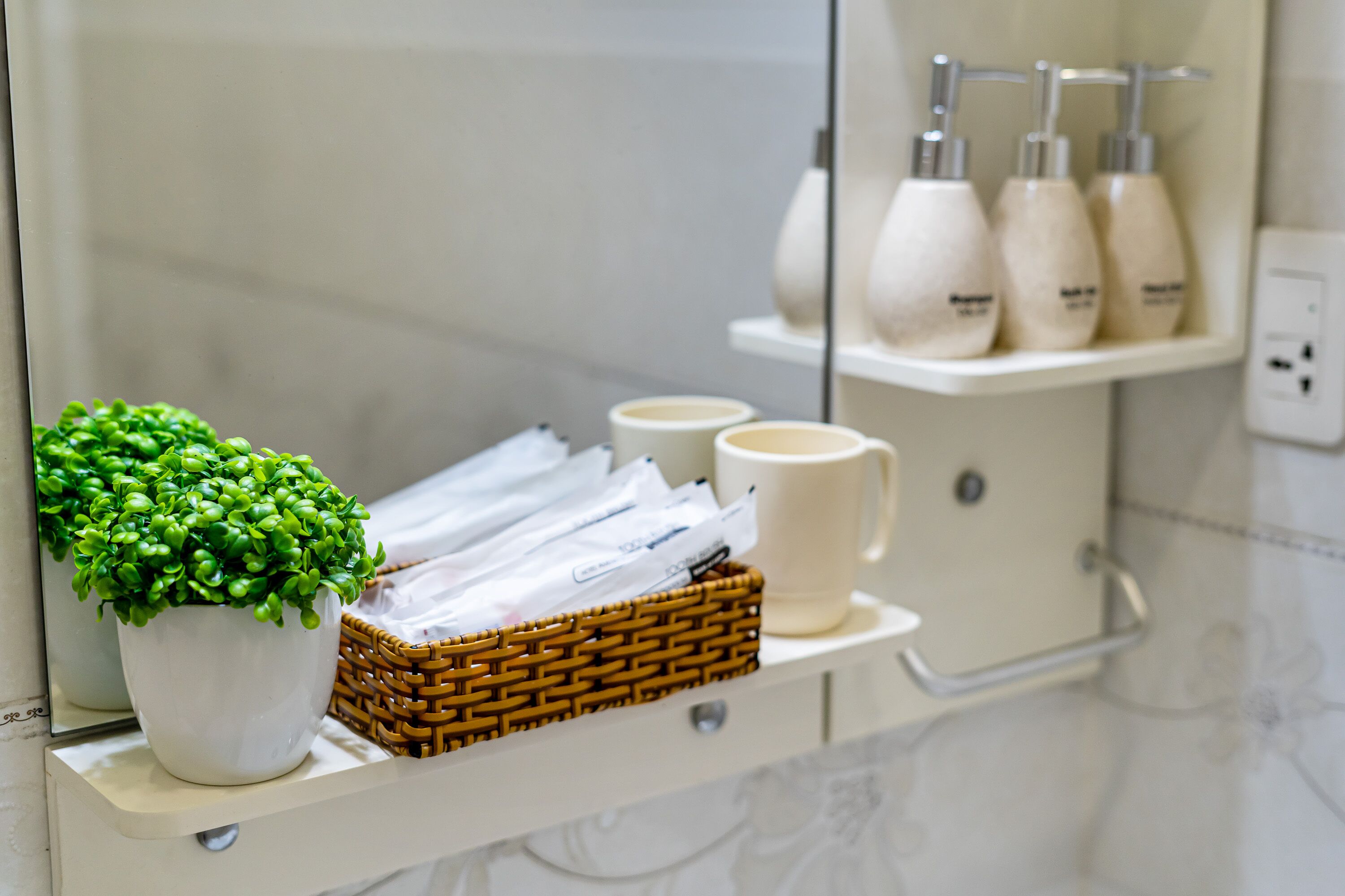 A bathroom vanity with a potted plant, a wicker basket, and toiletries.