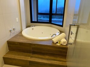 A modern bathroom with a freestanding bathtub, wooden steps, and a window with a view of a snowy landscape. - Apart Hotel Luxo Carpe Diem Boutique (Campos do Jordão)