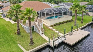 Ein Haus mit überdachtem Pool, einer Anlegestelle und Palmen.