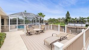 Eine überdachte Terrasse im Freien mit Pool, Sitzgelegenheiten und Blick auf ein Gewässer.