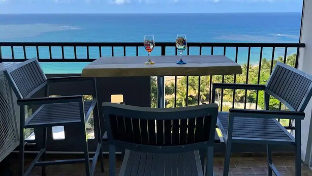 A balcony with a table and chairs overlooking the ocean.
