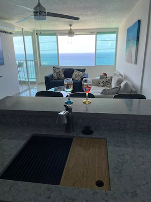 A modern kitchen with a marble countertop, a sink, and a ceiling fan. - Amazing View of the Ocean and sounds of the waves. (Luquillo)