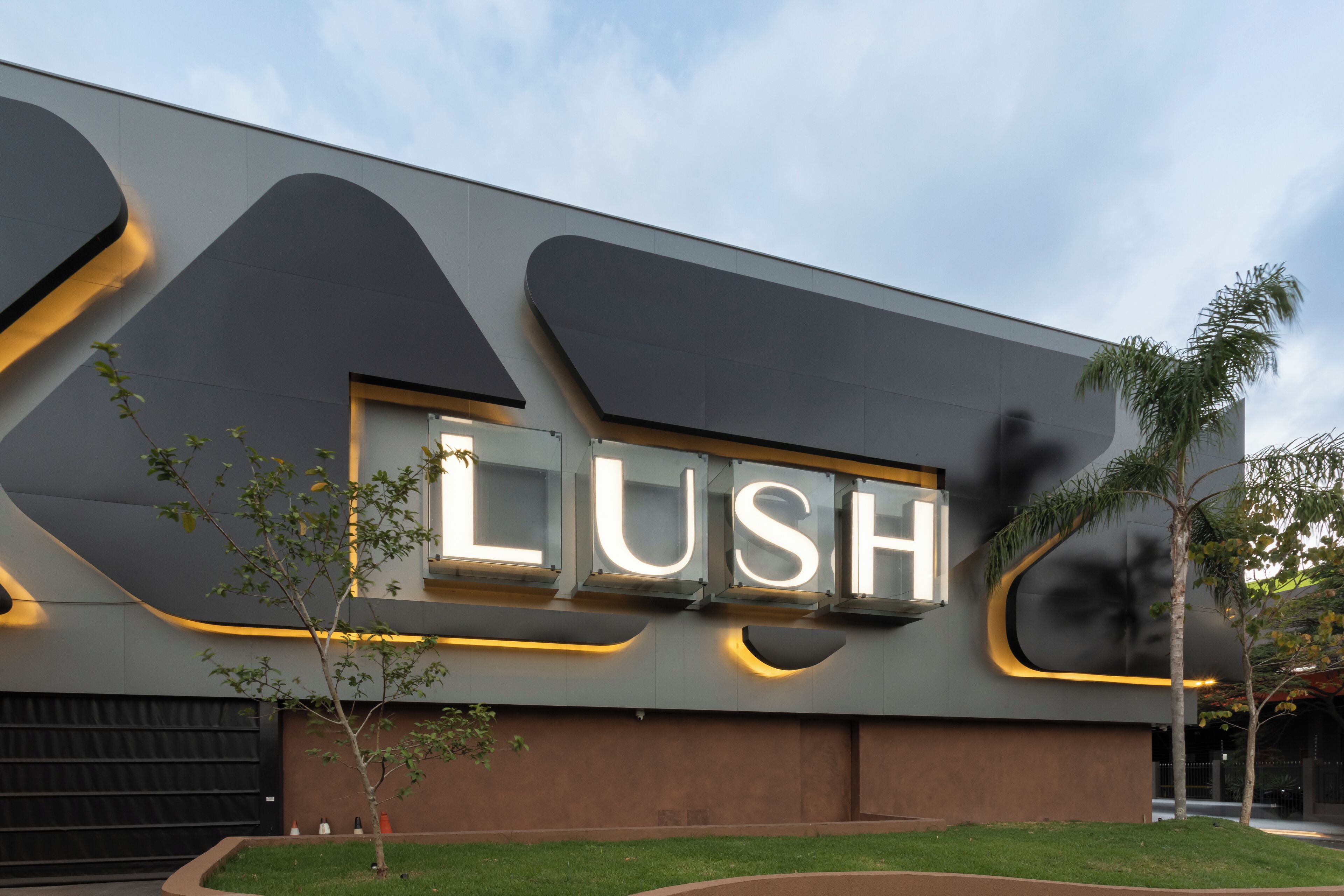 A modern building with a large illuminated sign reading "LUSH".