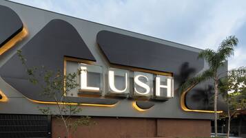 A modern building with a large illuminated sign reading "LUSH".