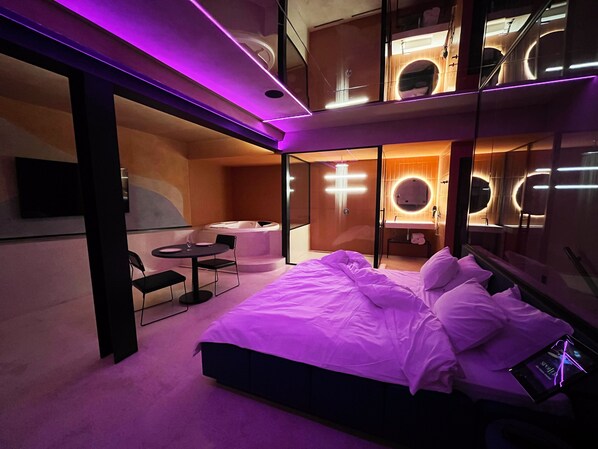 Un dormitorio moderno con una cama grande, una mesita pequeña y un jacuzzi.