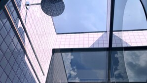 A modern building with a glass facade and a clear sky view.