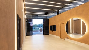 A modern interior with a long hallway, a circular mirror, and a door leading to an outdoor area.