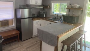 A compact kitchen with a refrigerator, stove, microwave, and sink. There is a window with a view of greenery outside. - Nature Escape - studio in the forest (Middletown)