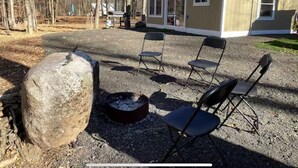 Eine Hütte mit Feuerstelle und Sitzgelegenheiten in einem Waldgebiet.