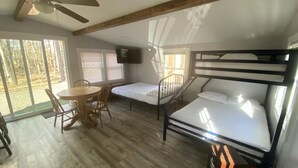 Ein Zimmer mit Etagenbett, Schreibtisch mit Stuhl, Fernseher und großen Fenstern.
