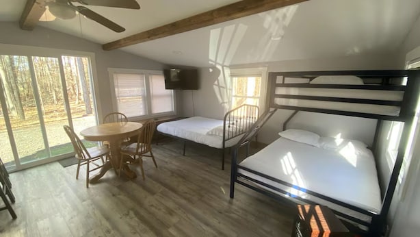 A room with a bunk bed, a desk with a chair, a television, and large windows. - Nature Escape - studio in the forest (Middletown)