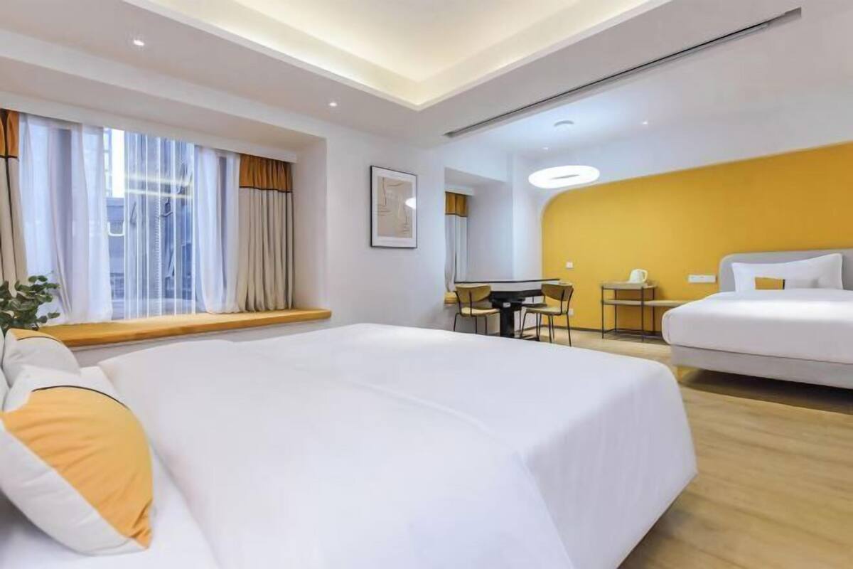 Habitació d'hotel amb un llit gran, un altre més petit, una taula i una cadira.