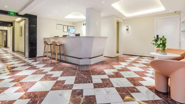 En hotellobby med en incheckningsdisk, en sittgrupp och ett golv med ett mönster.