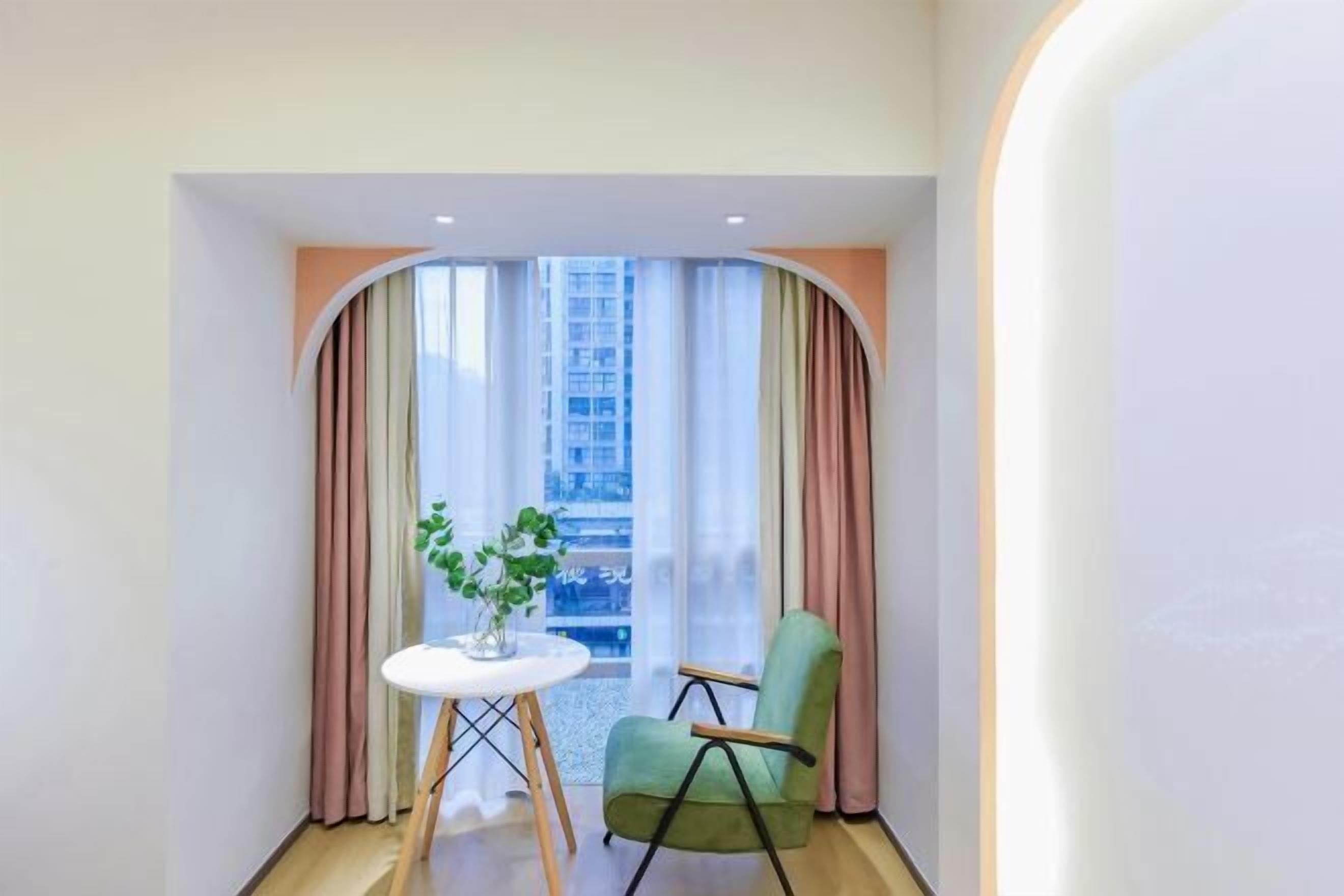 A small room with a window, a table with a plant, and a chair.