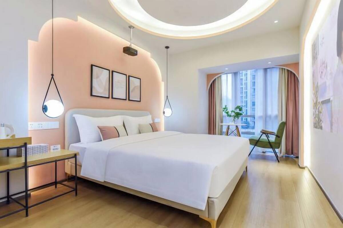 Habitació d'hotel moderna amb un llit gran, taules de nit, escriptori i vista a la ciutat.