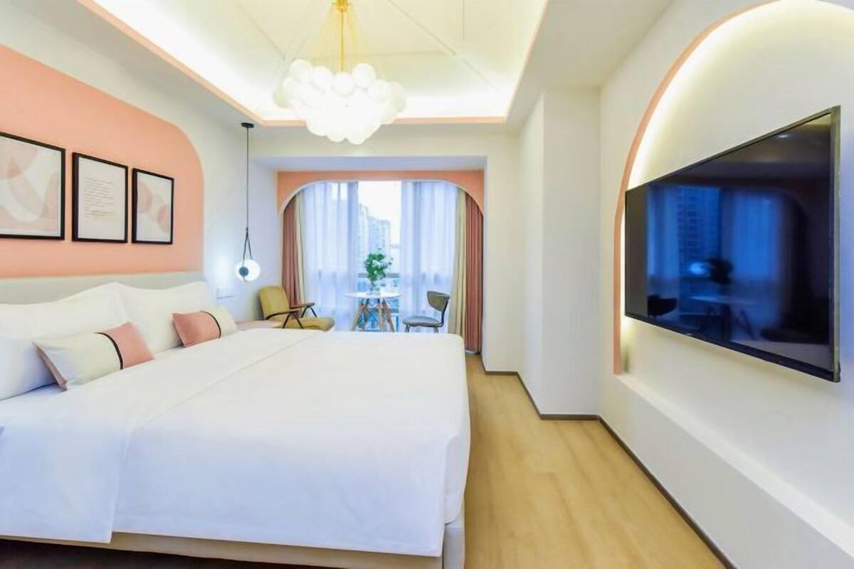Habitació d'hotel moderna amb un llit gran, un televisor fixat a la paret i vista a la ciutat per la finestra.
