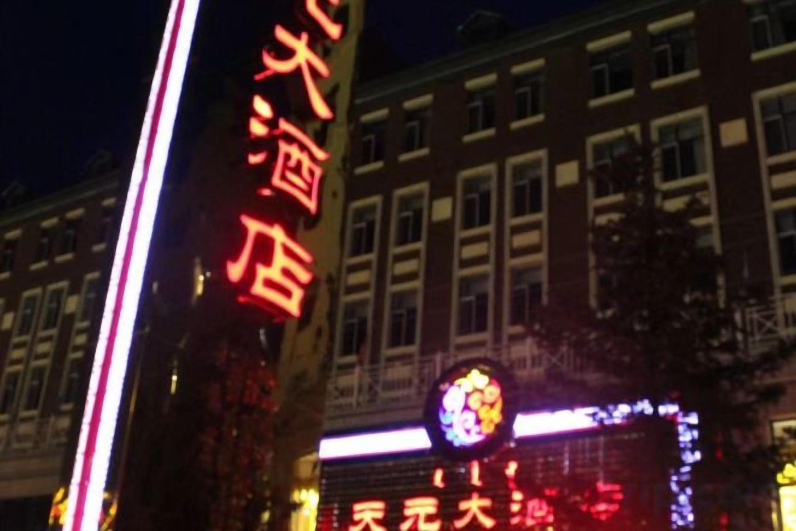 A building with illuminated signage, a prominent sign for a hotel, and a large illuminated logo.