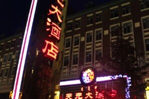 Un bâtiment doté d’une enseigne lumineuse, d’une grande enseigne indiquant la présence d’un hôtel et d’un logo de grande taille également illuminé.