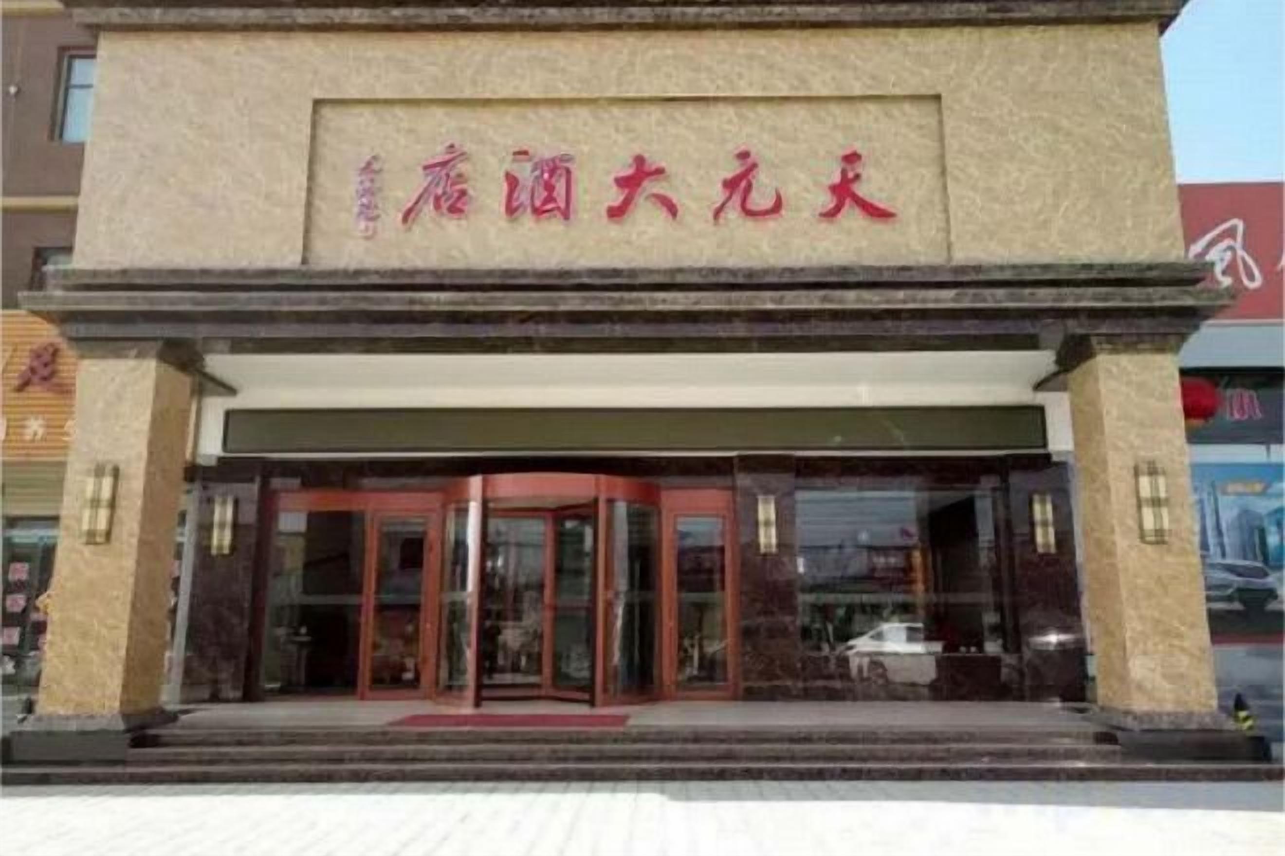 L'ingresso di un hotel con tenda rossa e insegna sopra le porte.