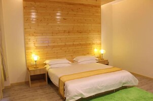 A room with a wooden headboard, a bed with white bedding, two bedside lamps, and a green rug.