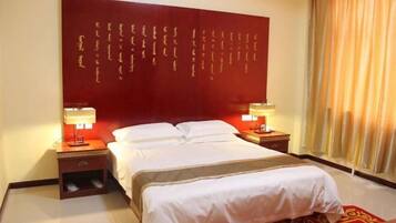 Quarto de hotel com uma cama grande, duas mesas de cabeceira, uma parede em vermelho com escrita dourada e uma janela com cortinas.