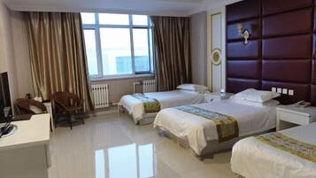 Quarto de hotel com duas camas, uma escrivaninha, uma cadeira e uma janela grande.