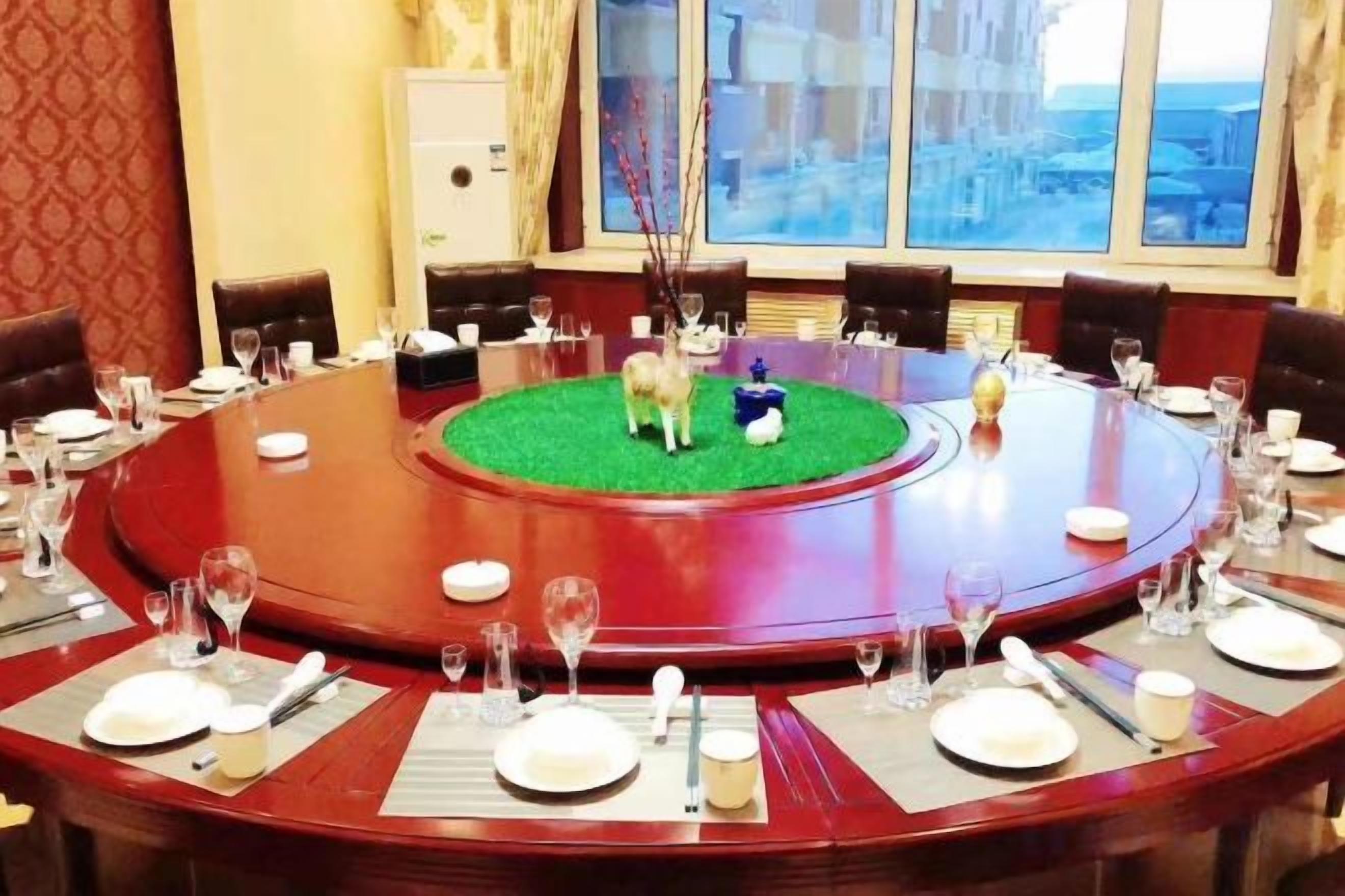 A round table with a central green area, surrounded by chairs and set with plates, glasses, and cutlery.